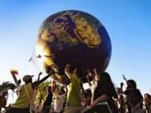 People outside supporting a large globe above their heads.